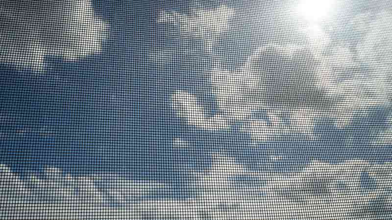 blue cloudy sky through fly screen