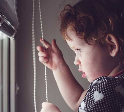 child playing with blind cord