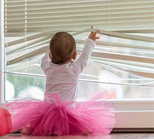 child playing with window blinds