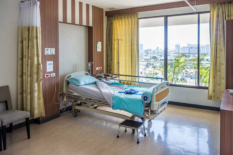 hospital bed surrounded by drawn back, yellow curtains